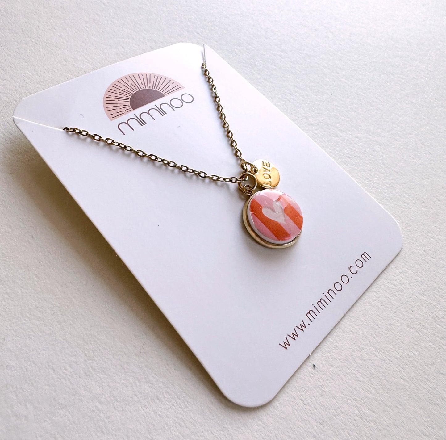Miminoo gold chain necklace with pink/orange striped heart charm & 'LOVE' tag.