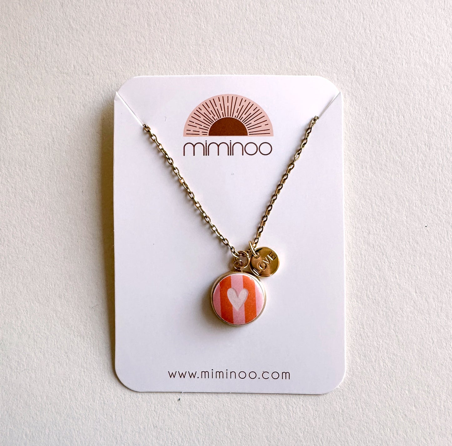 Gold chain necklace with round striped pink & orange heart charm & "LOVE" disc charm by Miminoo.