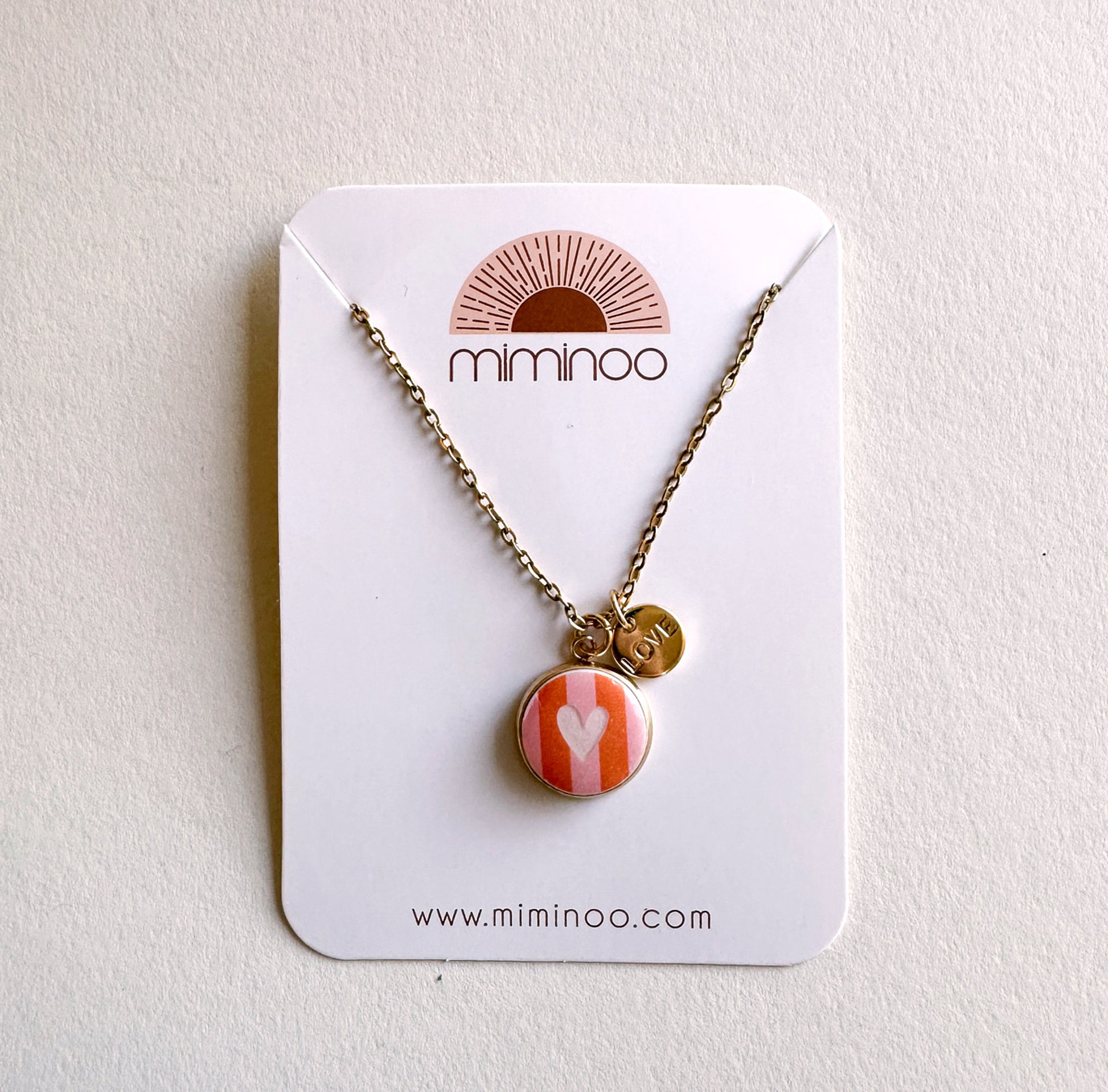 Gold chain necklace with round striped pink & orange heart charm & "LOVE" disc charm by Miminoo.